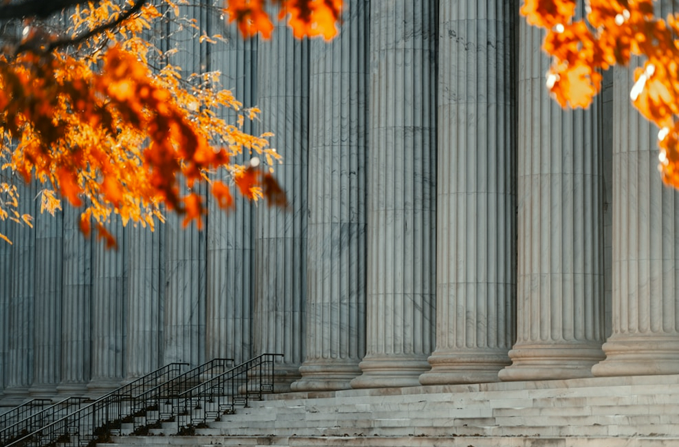 Stone courthouse columns framed by red autumn leaves