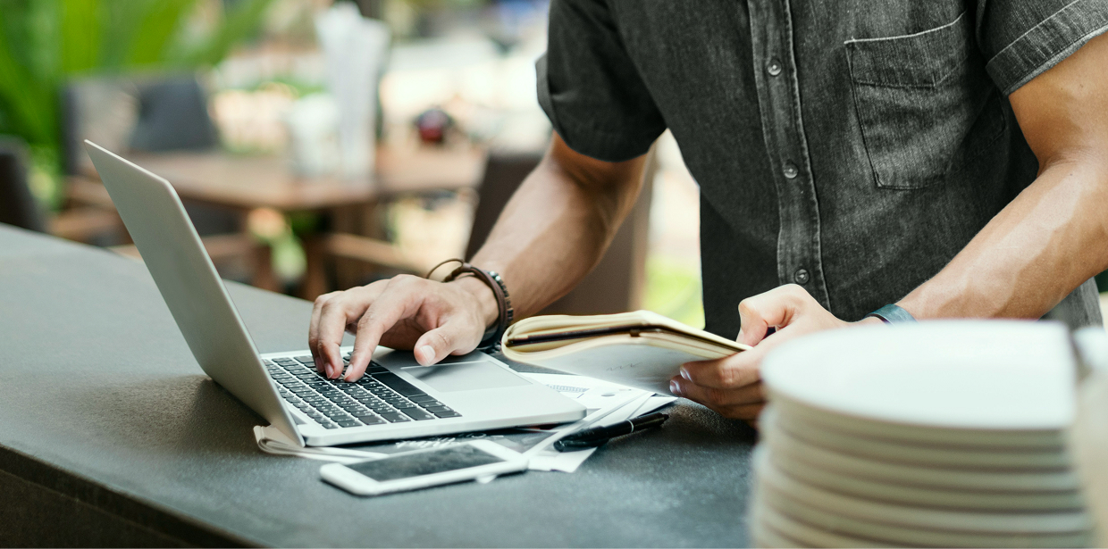 Cafe employee working on a laptop at the bar