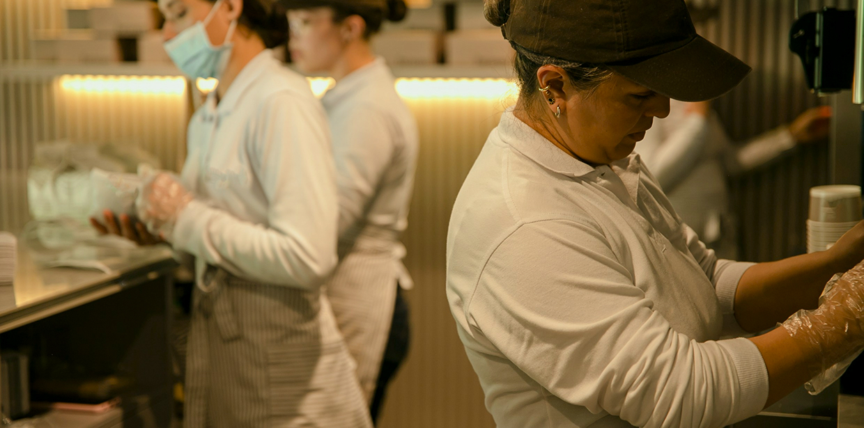 Kitchen workers in aprons preparing food together on a shift