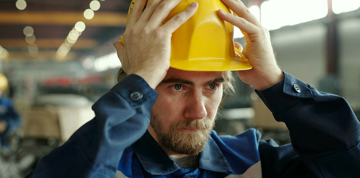 Construction worker putting on a yellow hard hat