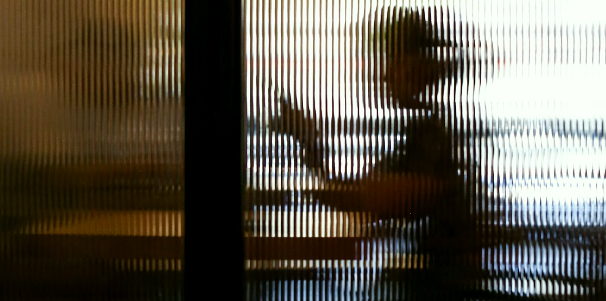 Silhouetted person behind fluted glass