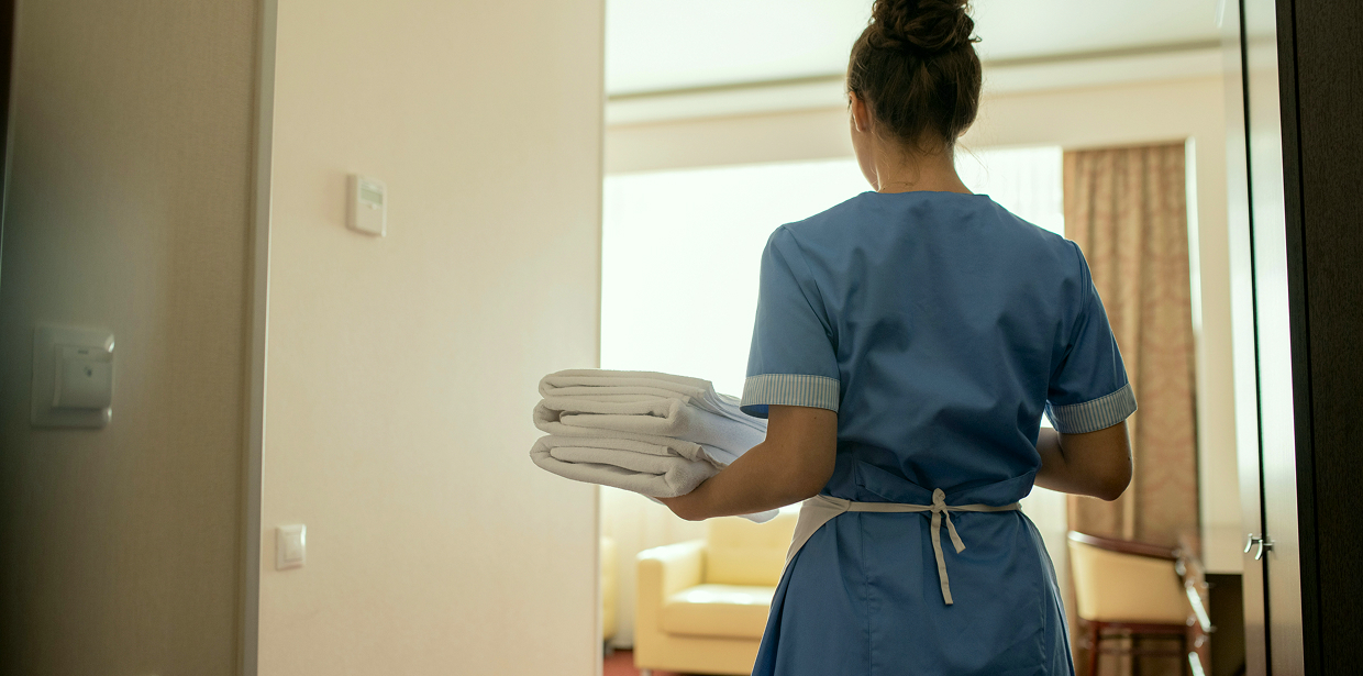 Hotel housekeeper carrying fresh towels into a room
