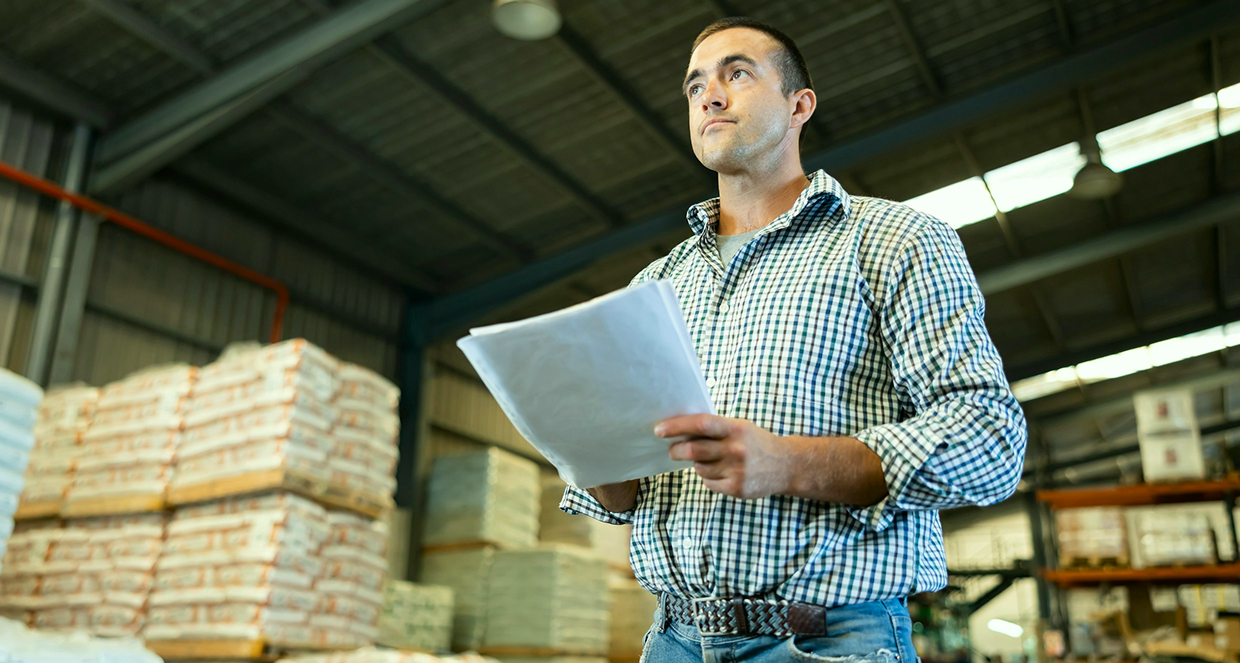 A man holding documents in a warehouse
