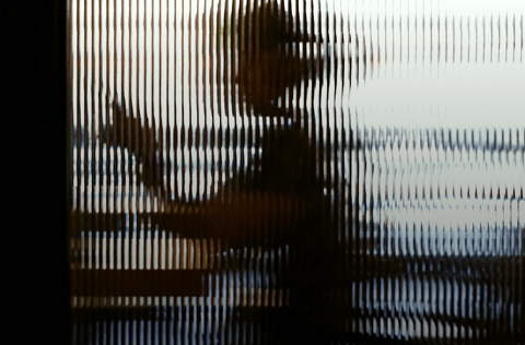 Silhouetted office worker behind textured glass