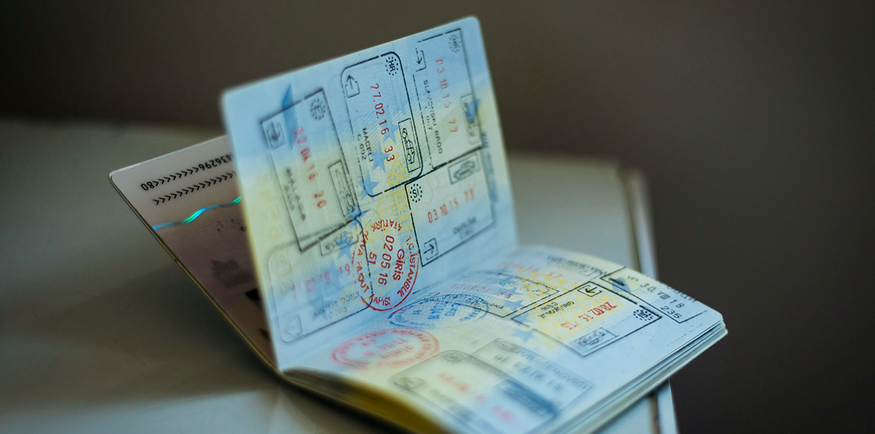 An open passport on a table, its pages filled with colorful entry and exit stamps from various countries