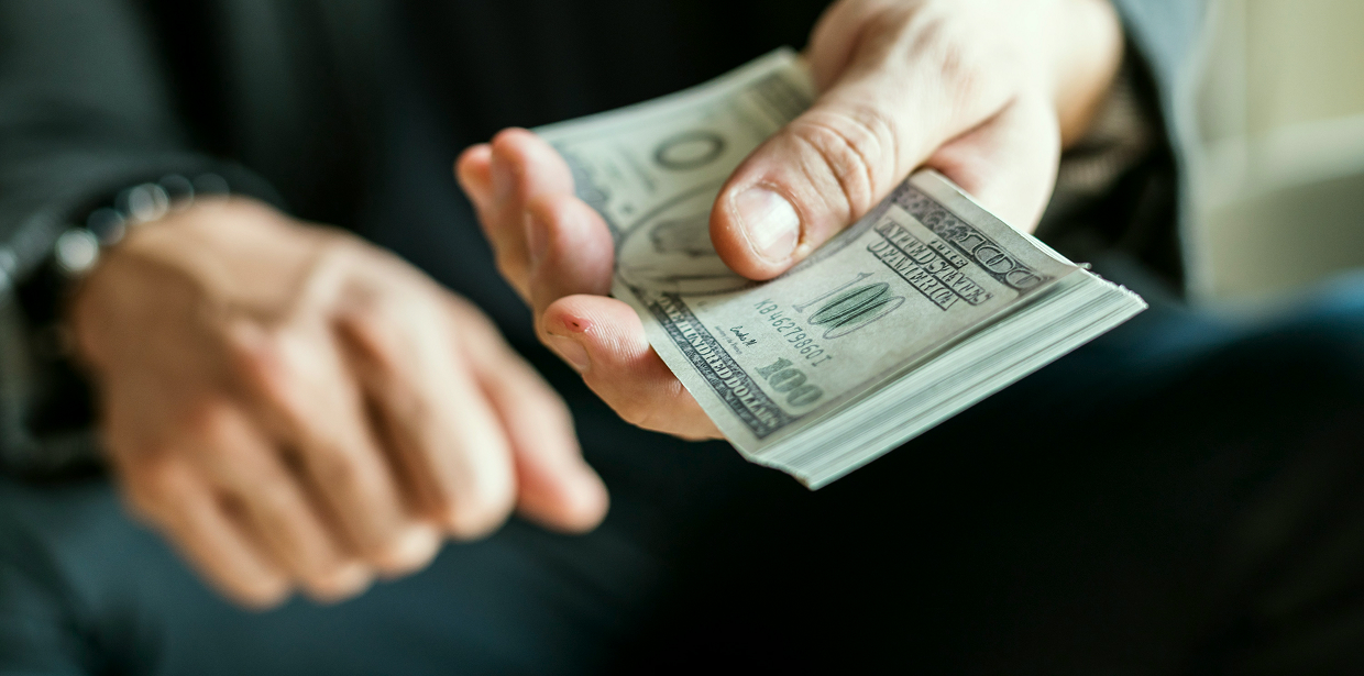 A person handing over a US dollar cash payment