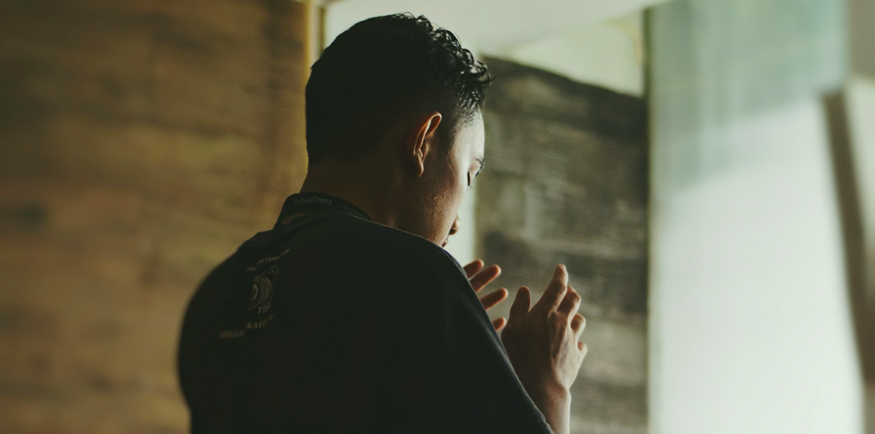 Person standing in prayer with hands raised