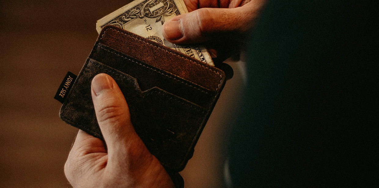 A person pulling cash from a leather wallet