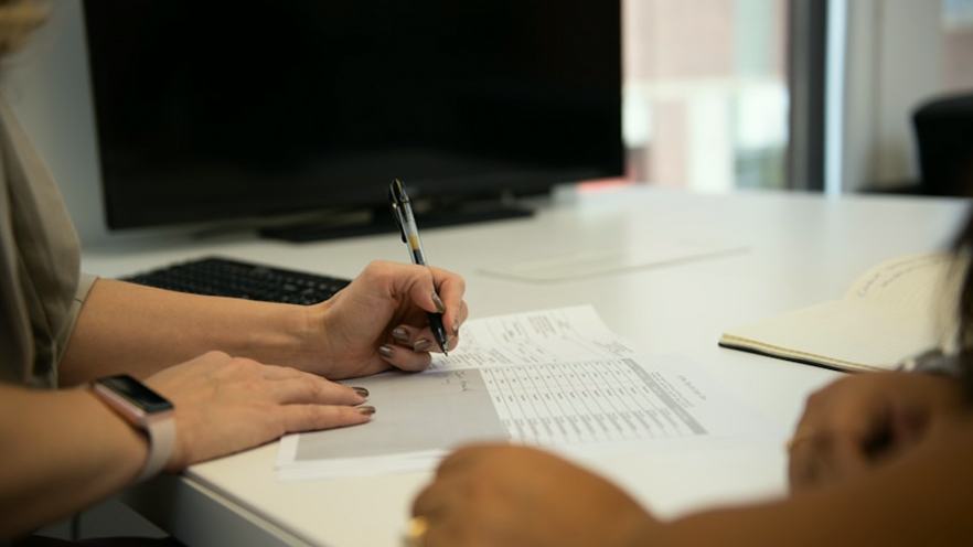 Person signing a document at an office desk