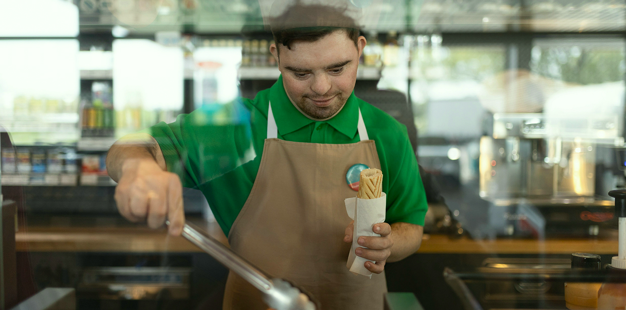 Food service worker with a disability preparing a hotdog behind a diner counter