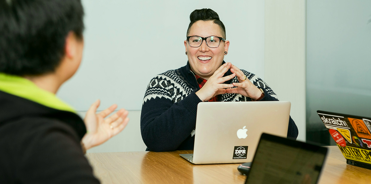 Smiling person looking at a college diploma while working on a laptop