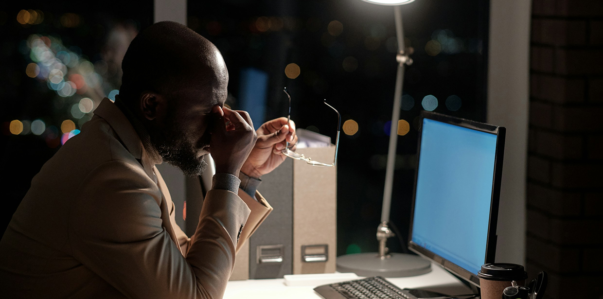 Tired employee working late at a computer in a darkened office
