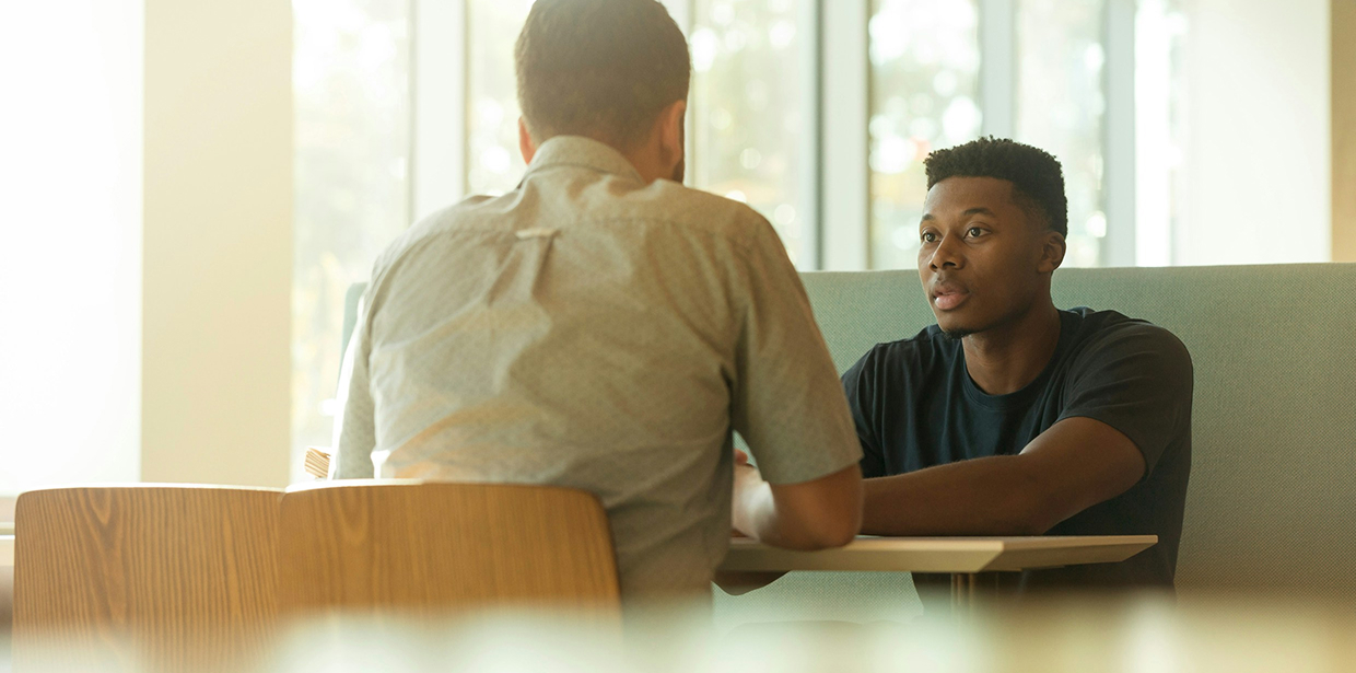 Two colleagues talking while sitting in a cafeteria