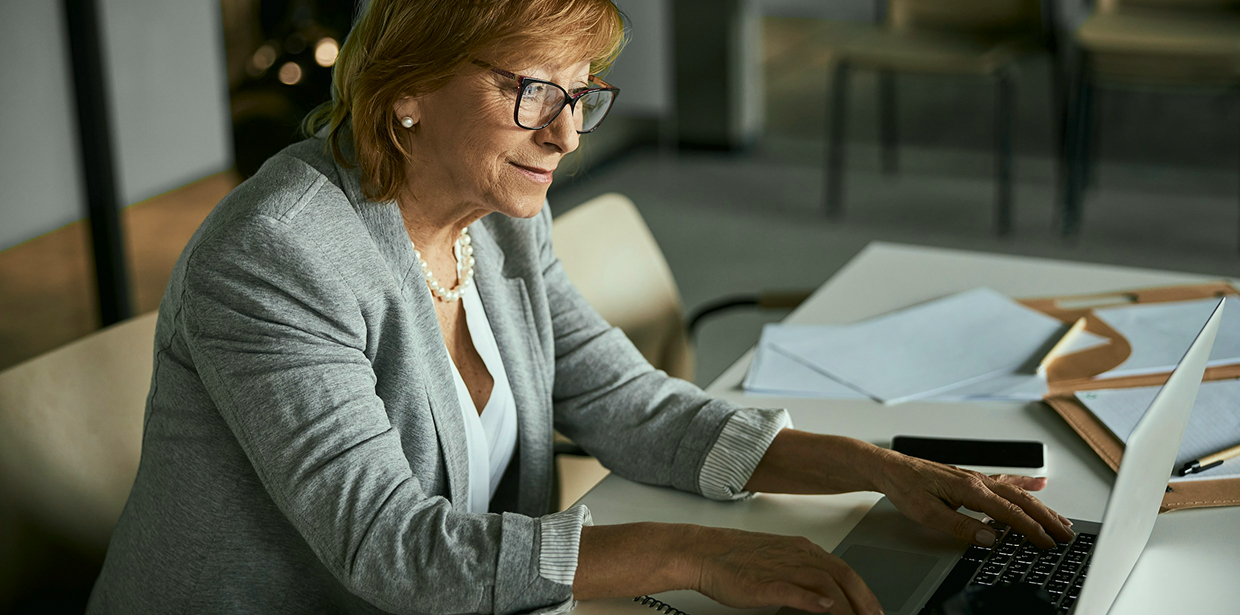 Executive in a business suit and glasses beside a laptop