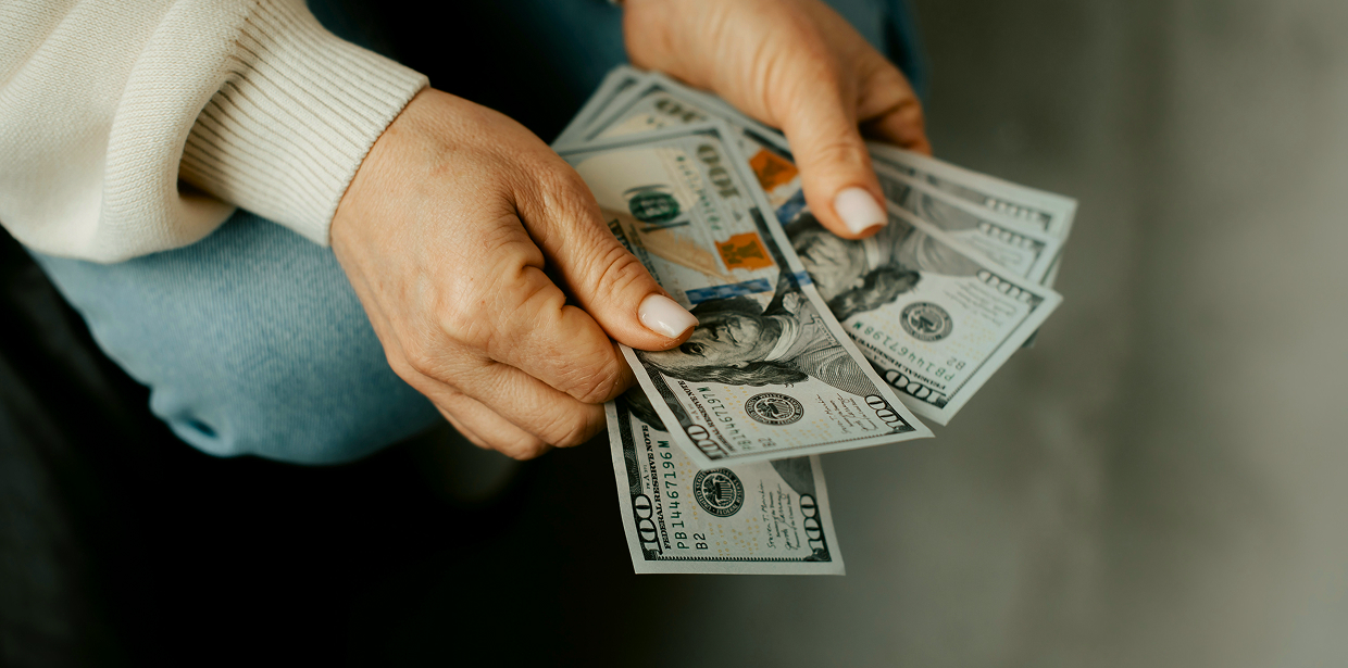 Person counting dollar bills at a table